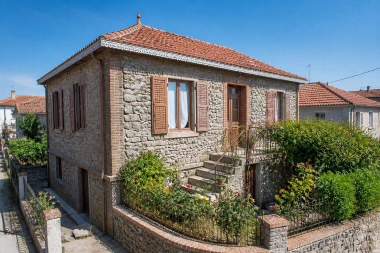 Maison en pierre avec volets bruns et toit en tuiles