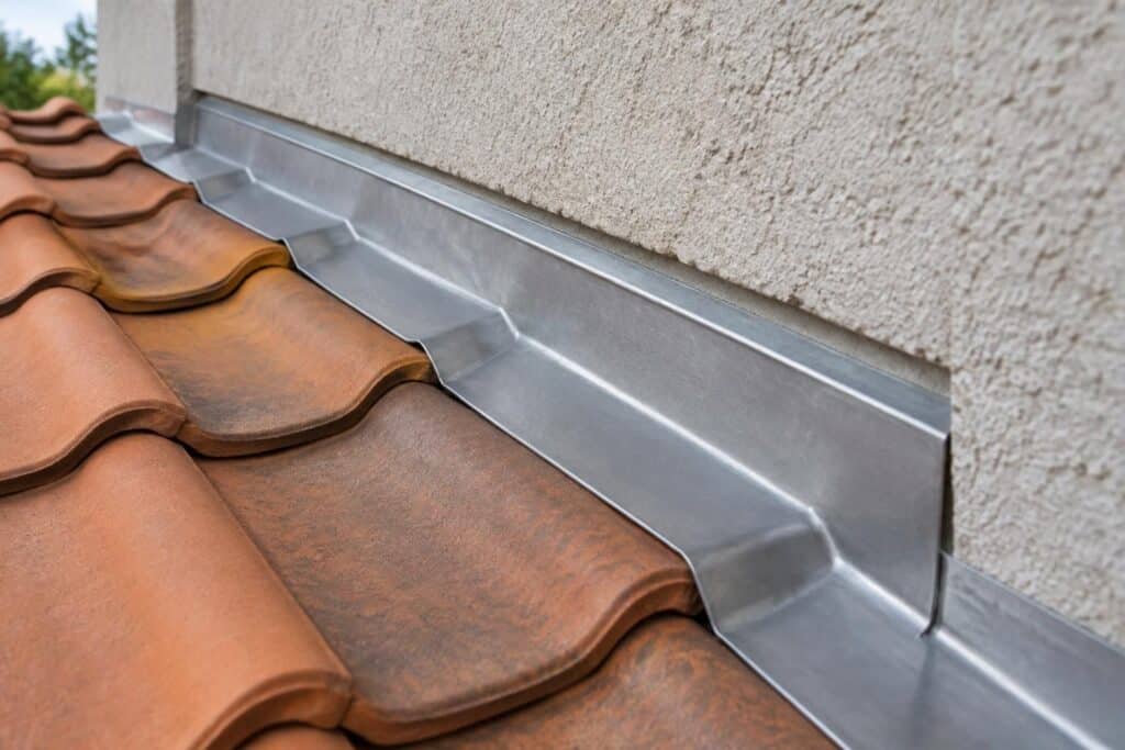 Tuiles ondulées terre cuite, mur beige et bande métallique grise au raccord